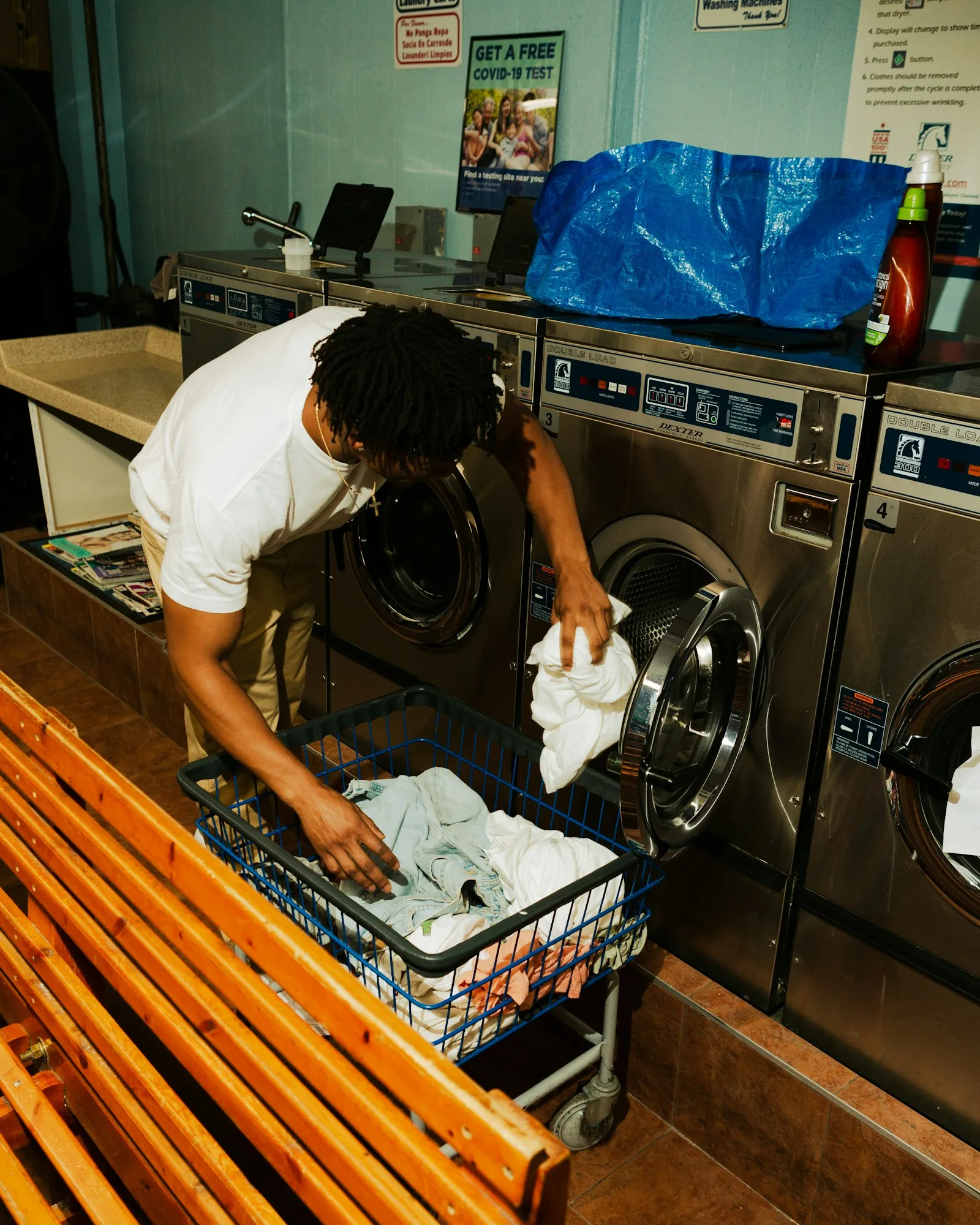 A laundry attendant unloading a dryer into a rolling cart