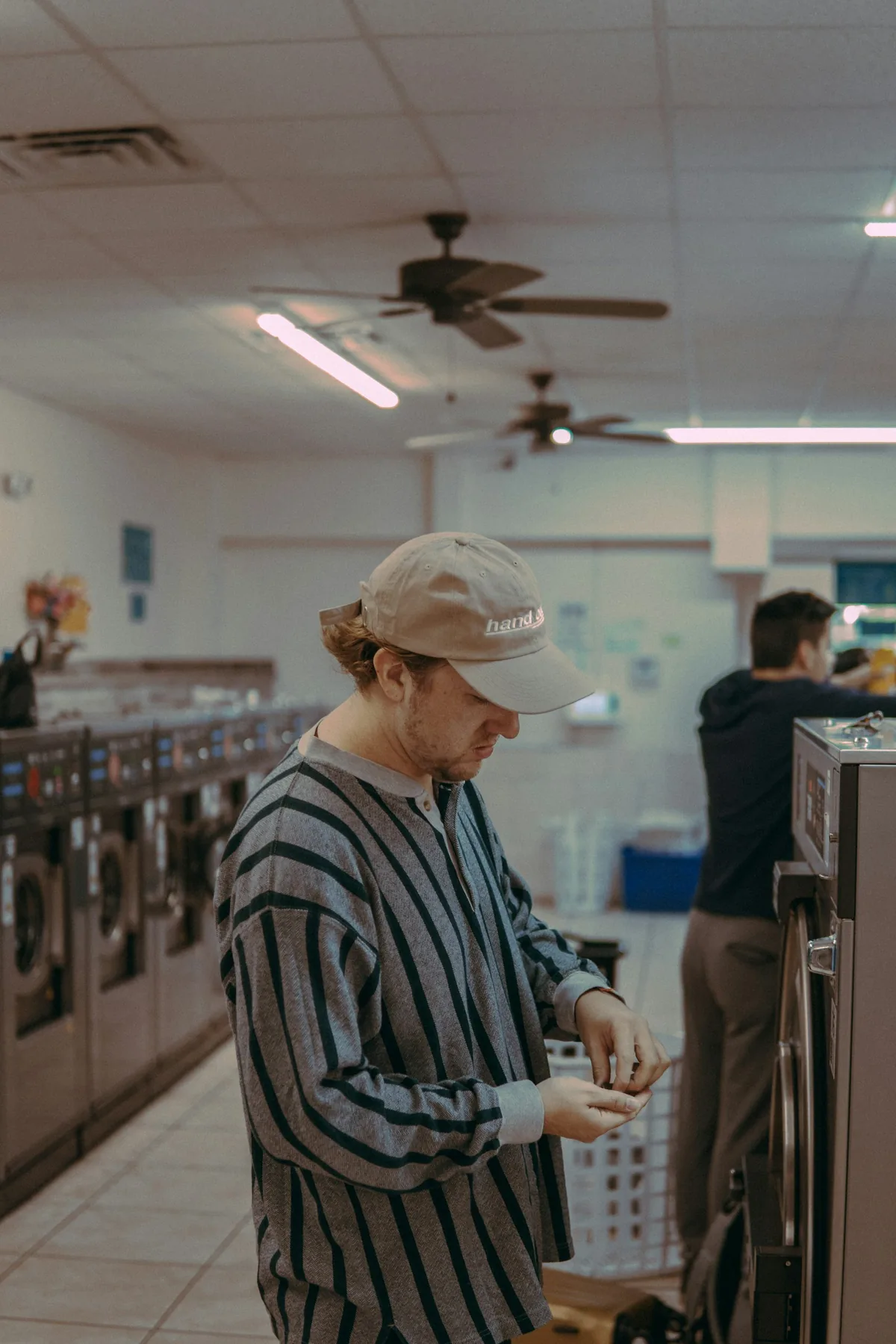 A customer starting a washer on a laundromat floor