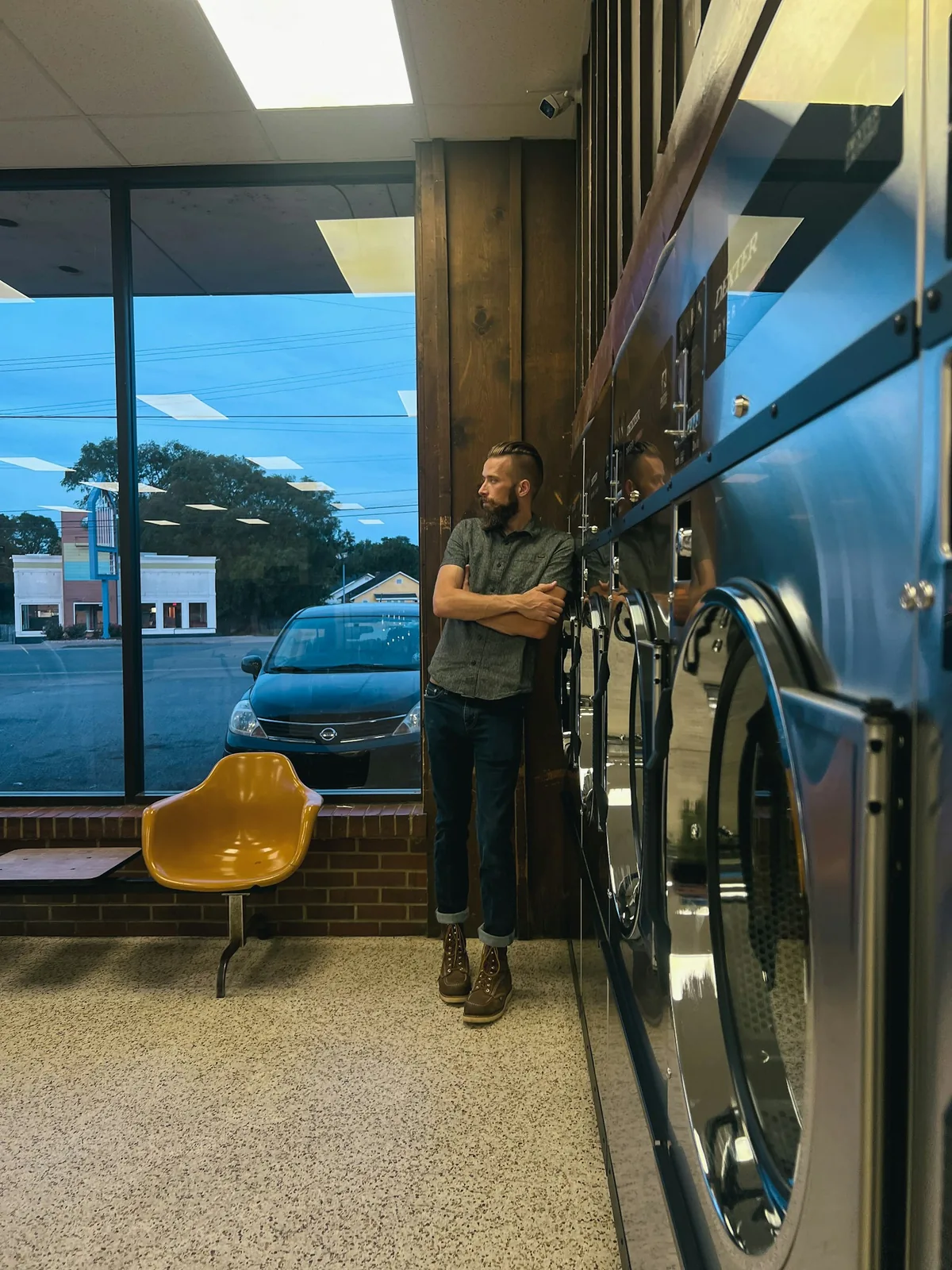 An operator standing beside a bank of washers near a storefront window