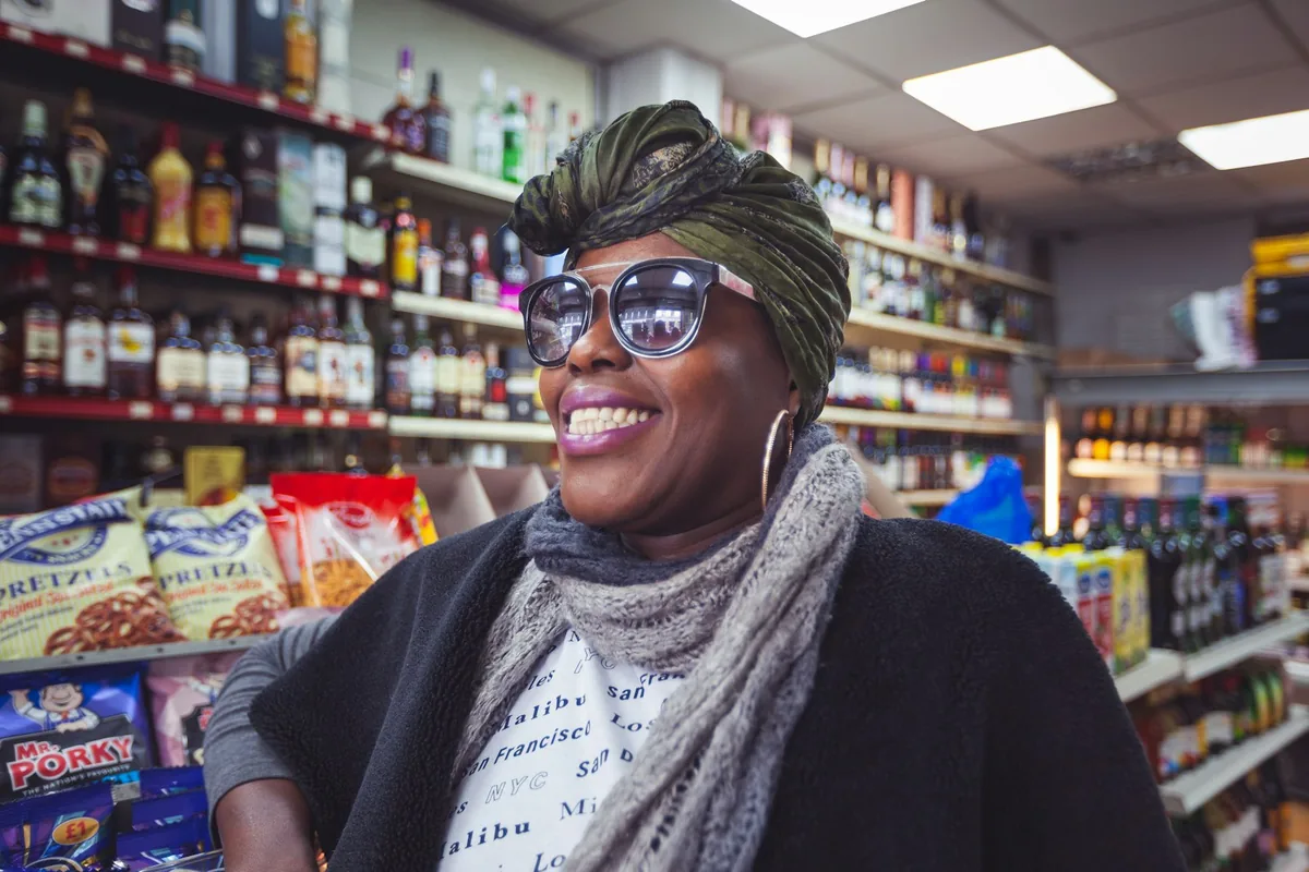 An independent shop owner laughing on the floor of their store