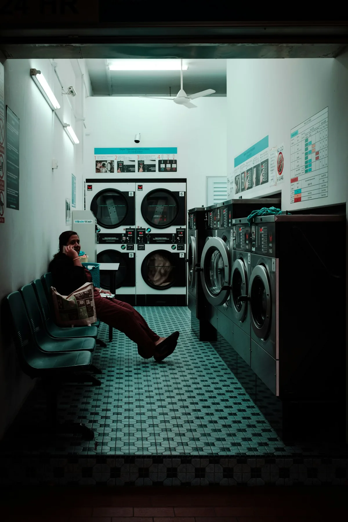 A person on a phone call while sitting inside a laundromat