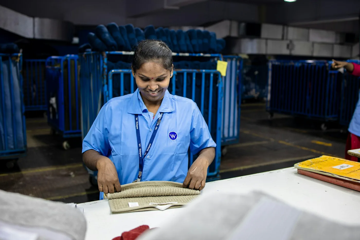 A worker folding finished laundry at a production table
